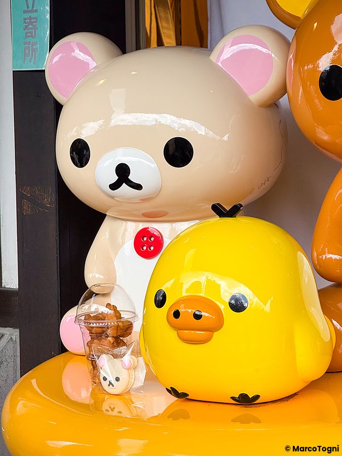 Mascotte all'ingresso a Rilakkuma Tea House con statuette di Rilakkuma e Kiiroitori vicino a snack.