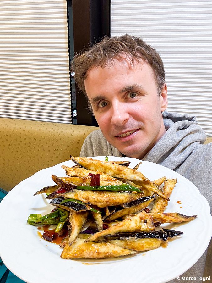 Marco Togni tiene un piatto di melanzane fritte presso il ristorante cinese Mara Daigaku a Ueno.