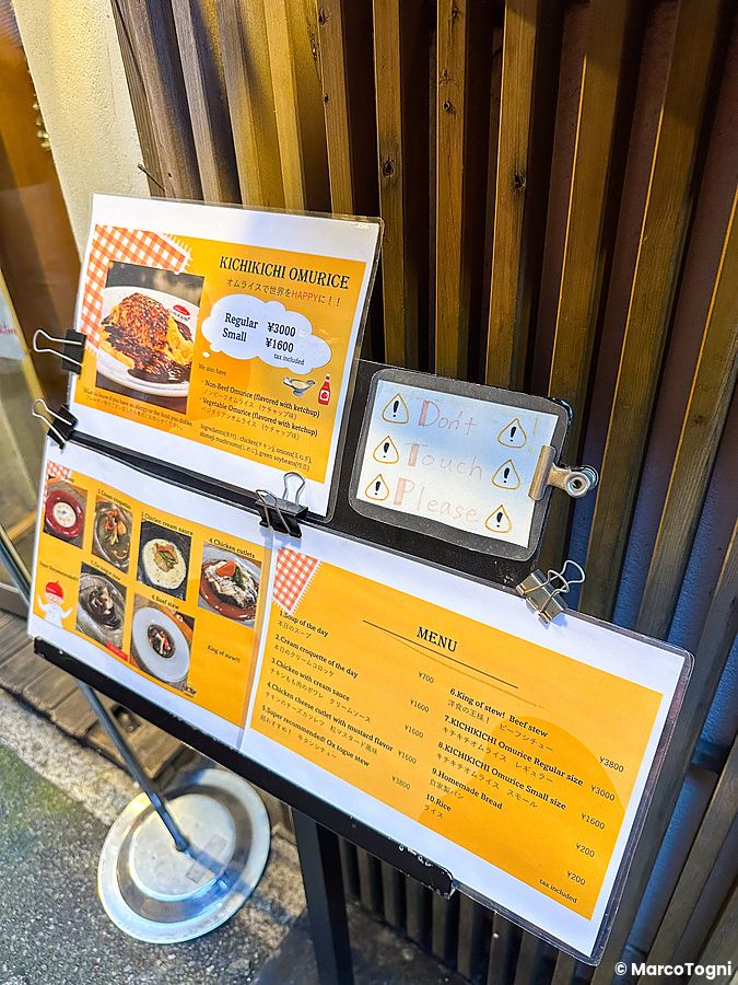 Veduta ravvicinata dell'ingresso e menu a Kichi Kichi Omurice con elenco dei piatti e un avviso di non toccare.