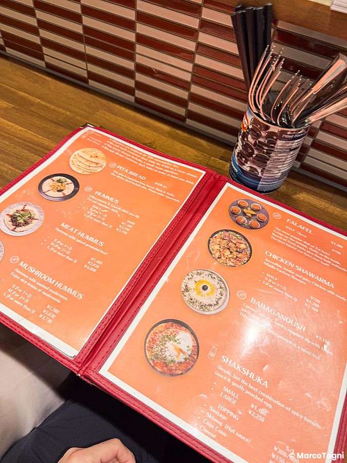 Il menu del Ristorante Telaviv a Kyoto aperto su un tavolo con le proposte di piatti israeliani.