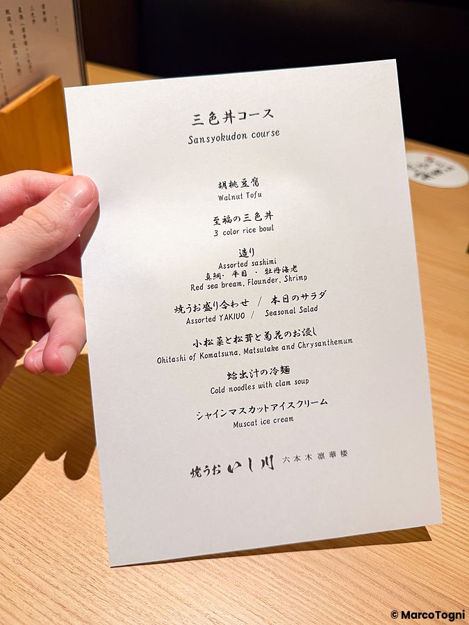 Un menu stampato tenuto in mano presso il ristorante Yakiuo Ishikawa a Roppongi, Tokyo.