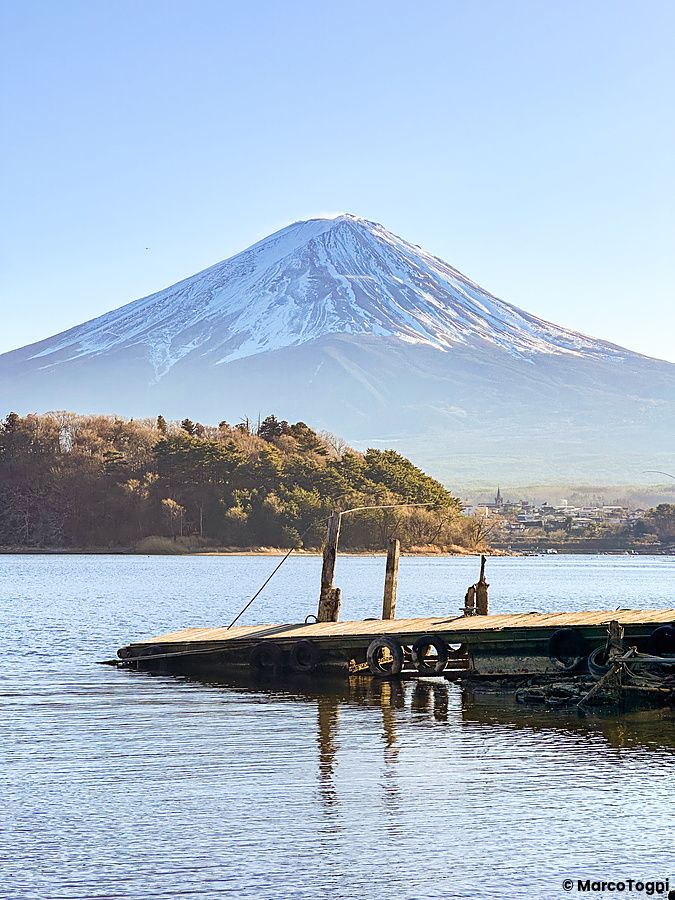 Il Monte Fuji innevato sovrasta il lago Kawaguchi visto dal pontile in legno del Parco Oishi.
