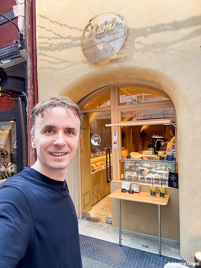 Marco Togni sorridente posa davanti all'ingresso della pasticceria Naki vegan sweets a Namba, Osaka.