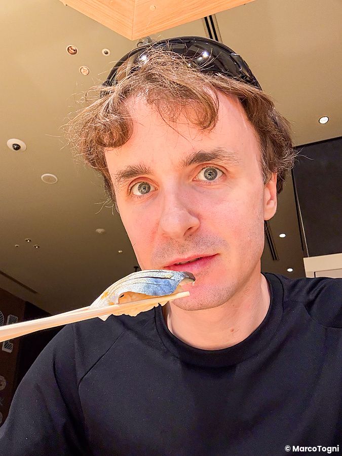 Marco Togni sostiene un nigiri di kohada con le bacchette all'interno del Sushi & Bar Fujiro Marunouchi Tokyo.