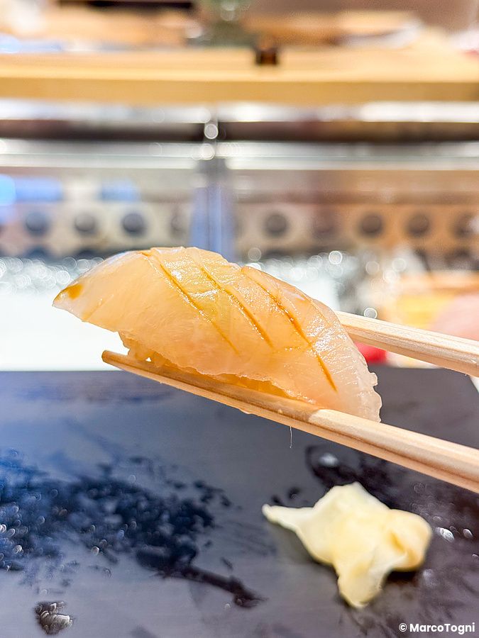Nigiri sollevato con bacchette al Sushi & Bar Fujiro Marunouchi Tokyo.