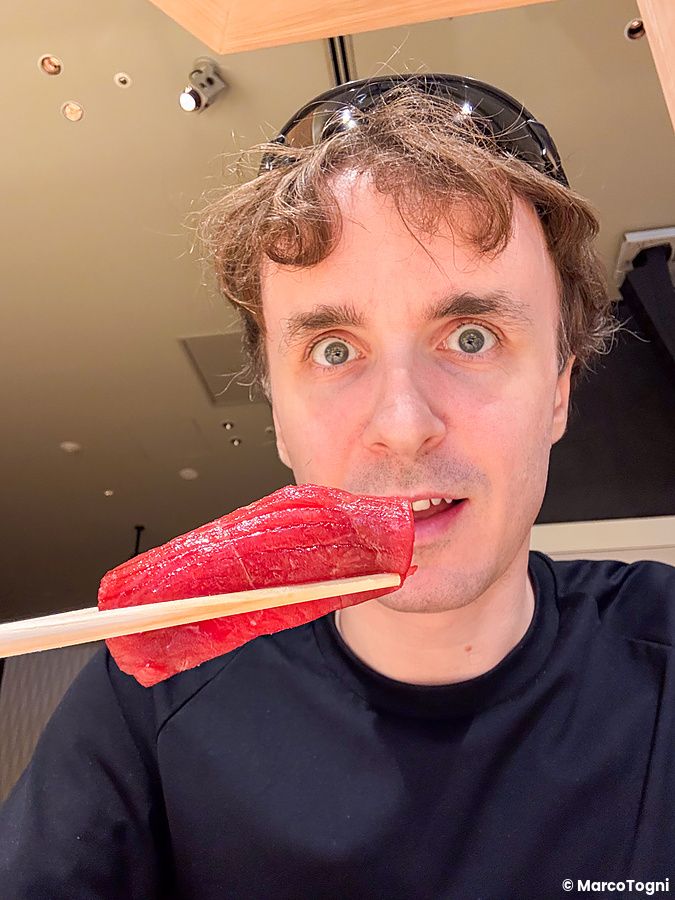 Marco Togni tiene un nigiri di tonno con le bacchette vicino alla bocca nel Sushi & Bar Fujiro Marunouchi Tokyo.
