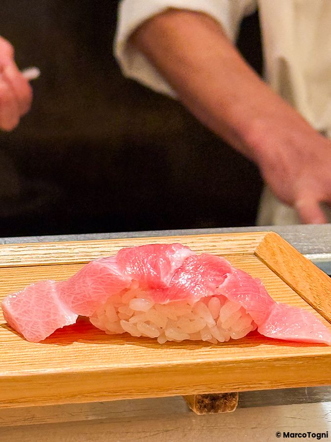 Un nigiri di tonno posizionato su un vassoio di legno presso il ristorante Sushimaru a Shinjuku.