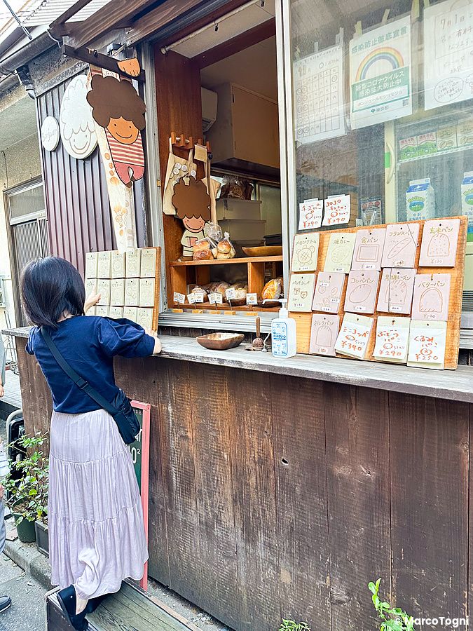 Una donna osserva il menu esterno della panetteria Bonjour mojo2 nel quartiere di Nezu a Tokyo.
