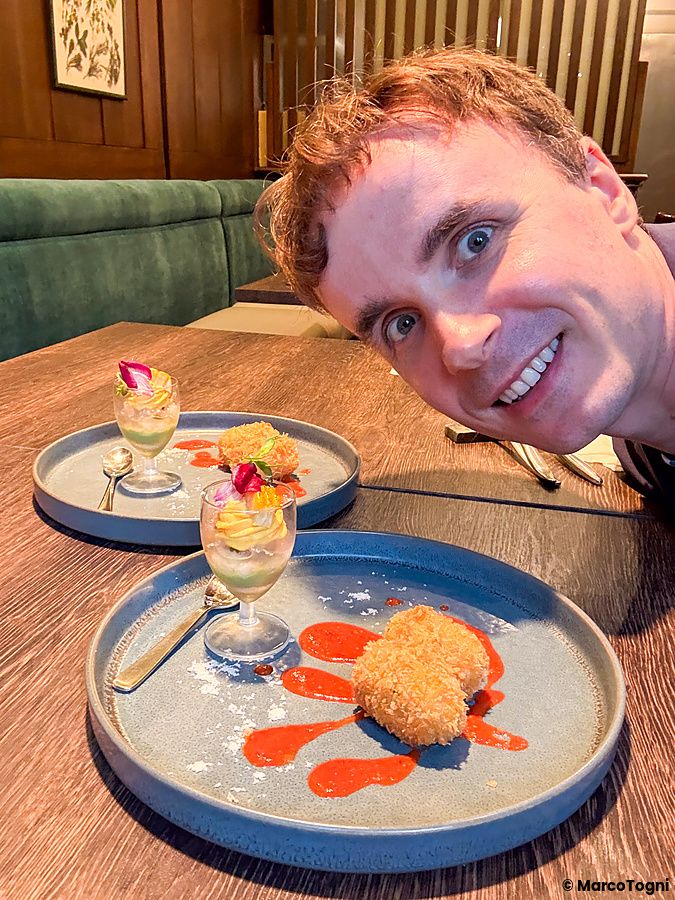 Marco Togni sorride accanto a due piatti con parfait di verdure e una crocchetta con carne vegana al Green Italian Torcia.