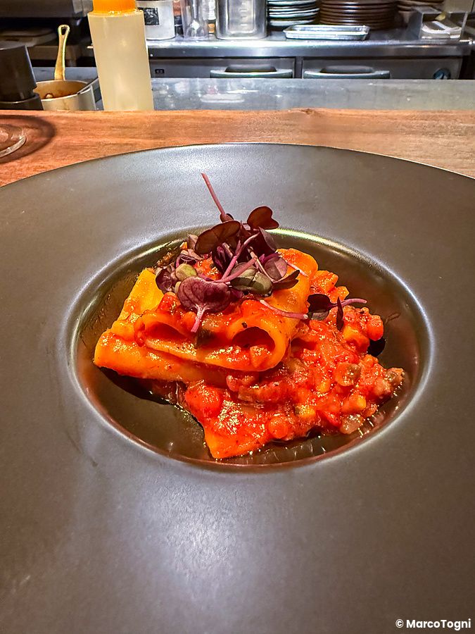 Pasta con ragù di kinzanji miso, un piatto vegano servito in un piatto scuro presso il ristorante Mushroom Tokyo.