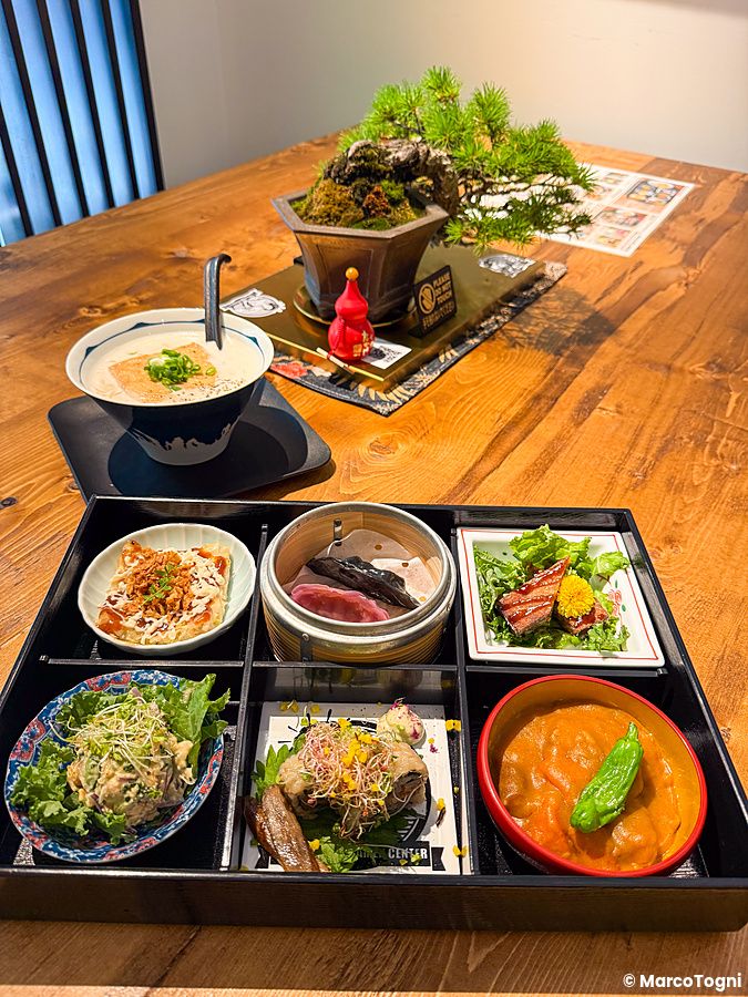 Un piatto misto al Tokyo Vegan Ramen Center composto da varie ciotole colorate su un vassoio nero.
