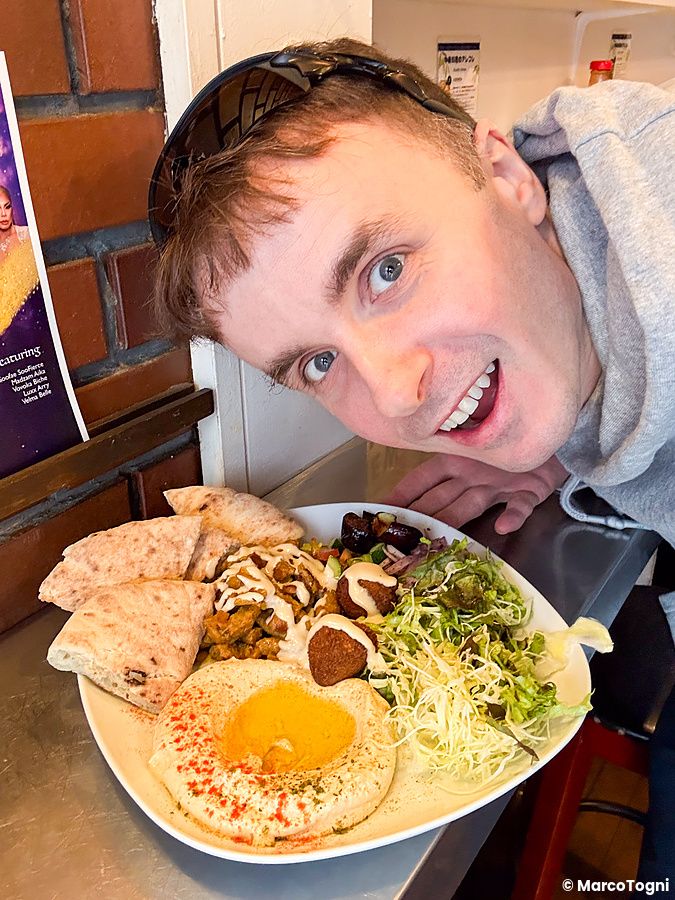 Marco Togni posa accanto a un piatto misto vegano al ristorante Falafel Sababa a Osaka.