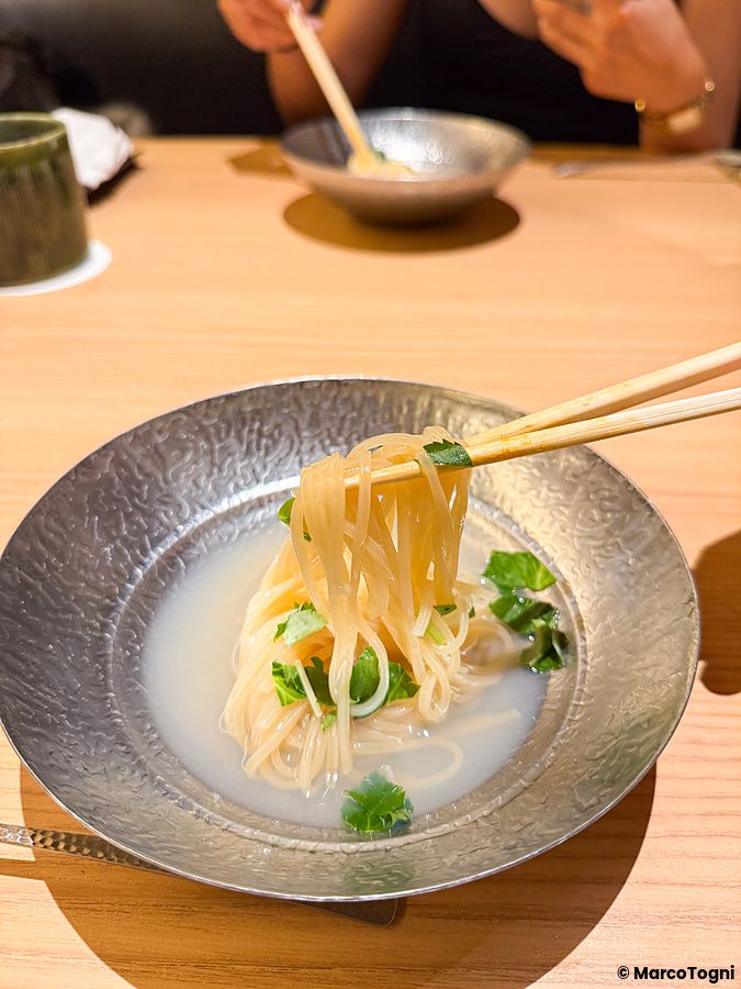 Un piatto di reimen con noodles e brodo servito in una ciotola di metallo martellato al ristorante Yakiuo Ishikawa.