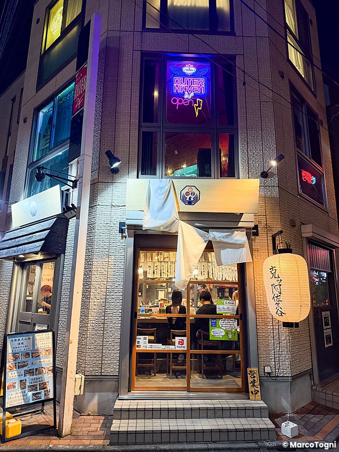 Un edificio commerciale ad Asagaya con vetrate illuminate, persone sedute all'interno e una lanterna giapponese all'esterno.