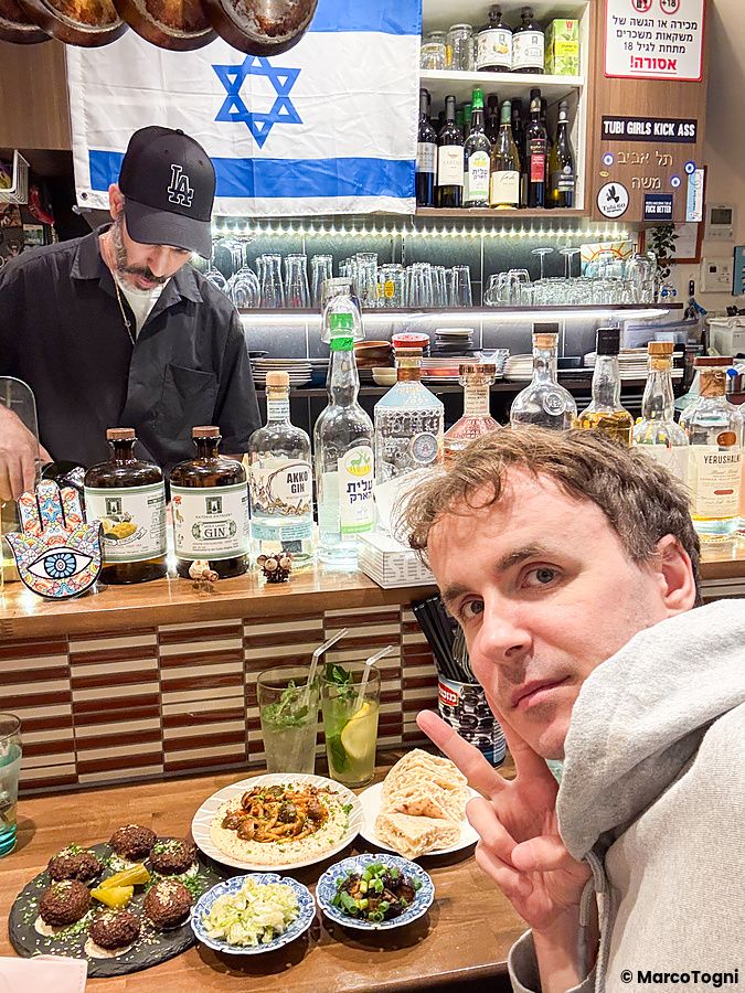 Marco Togni si scatta un selfie al ristorante Telaviv a Kyoto con piatti di falafel e hummus sul tavolo.