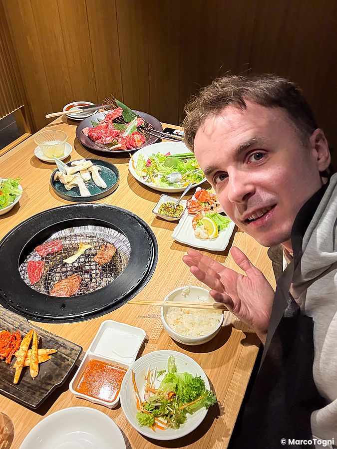 Marco Togni sorridente siede a un tavolo con griglia per yakiniku presso il ristorante Toraji.
