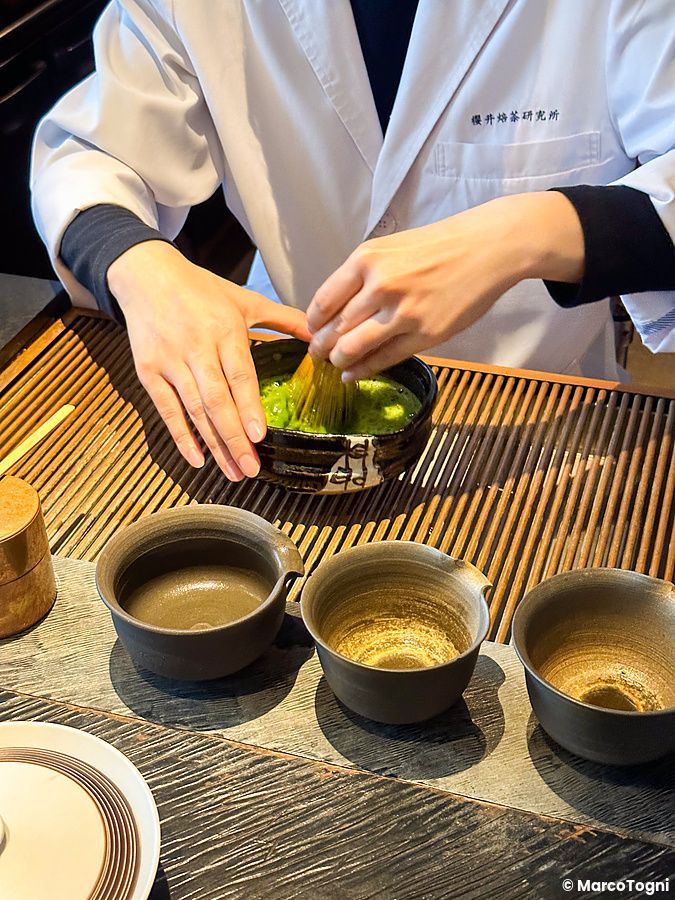 Un individuo prepara il tè matcha con un chasen in una ciotola di ceramica presso Sakurai Japanese Tea Experience a Tokyo.