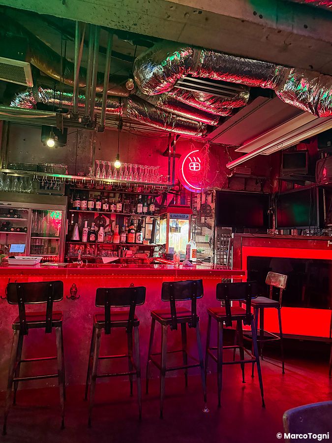 Interno del ristorante Neo Shinjuku Atsushi a Shinjuku, caratterizzato da luci al neon rosse e un hamburger vegano.