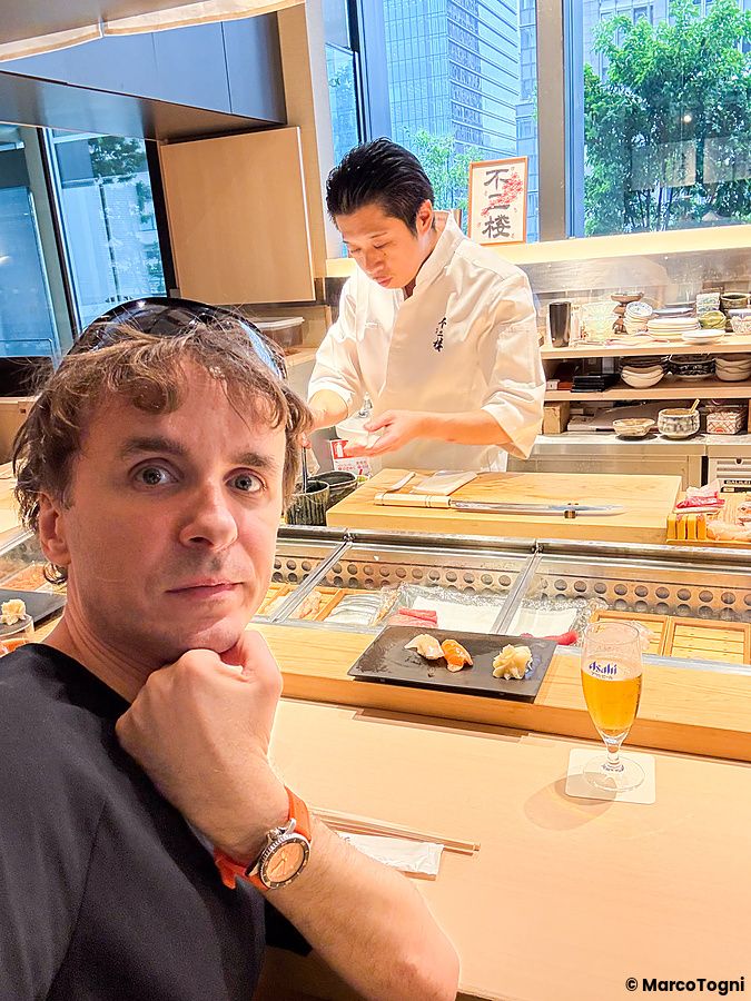 Marco Togni seduto al bancone mentre uno chef prepara sushi al Sushi & Bar Fujiro Marunouchi Tokyo.