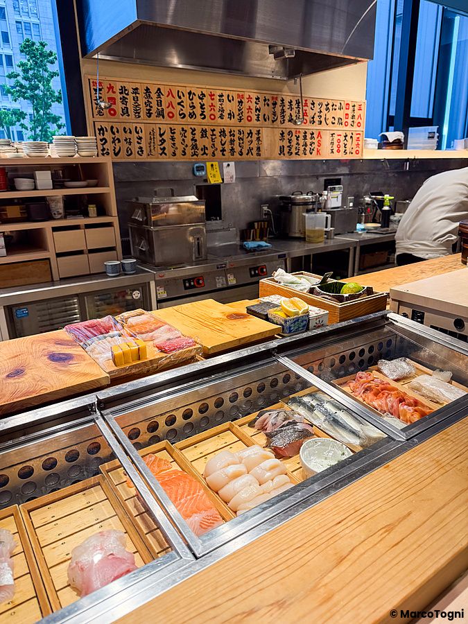 Bancone in legno con pesce fresco esposto al Sushi & Bar Fujiro Marunouchi Tokyo, all'interno del Marunouchi Building.