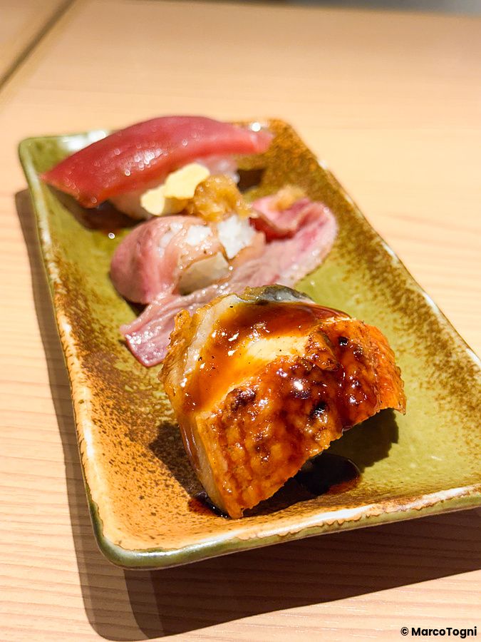 Tre pezzi di sushi assortito su un vassoio di ceramica presso il Ristorante New Sushi Center Harukiya a Osaka.