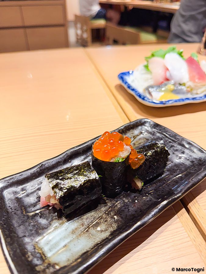 Sushi con uova di salmone su piatto scuro al Ristorante New Sushi Center Harukiya di Osaka.