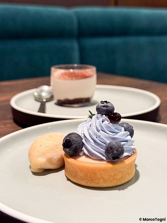 Una tartelletta ai mirtilli con crema e un tiramisù vegano serviti su piatti chiari al ristorante Green Italian Torcia.