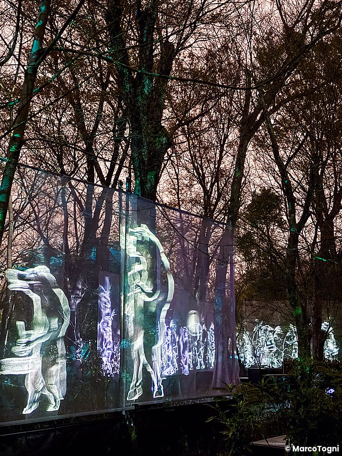 Proiezioni digitali di figure stilizzate su schermi trasparenti all'interno del teamLab Botanical Garden Osaka.