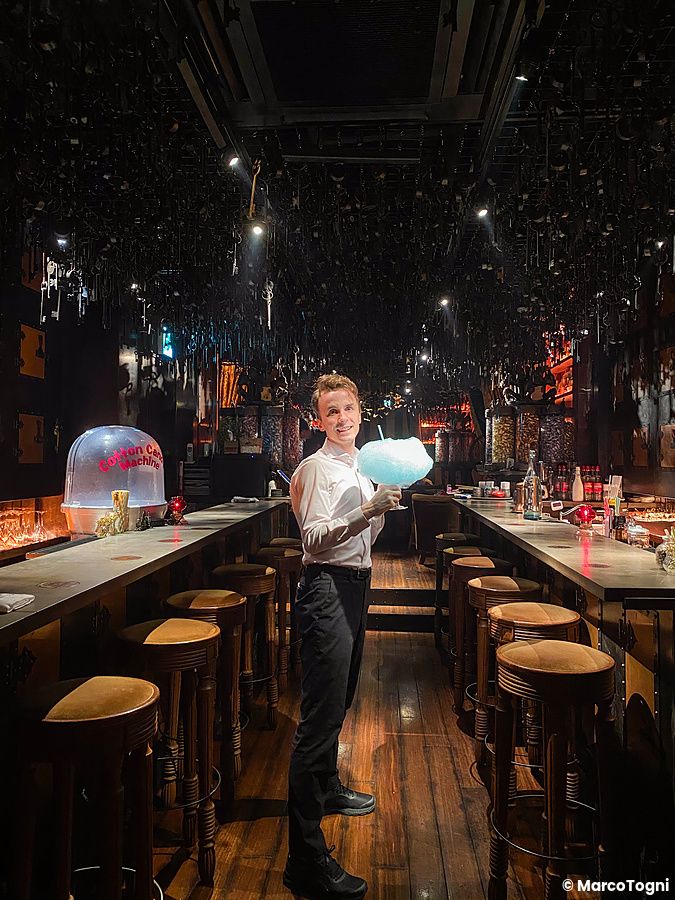 Marco Togni in camicia bianca tiene un drink con zucchero filato all'interno del bar Tír na nÓg a Ginza, Tokyo.