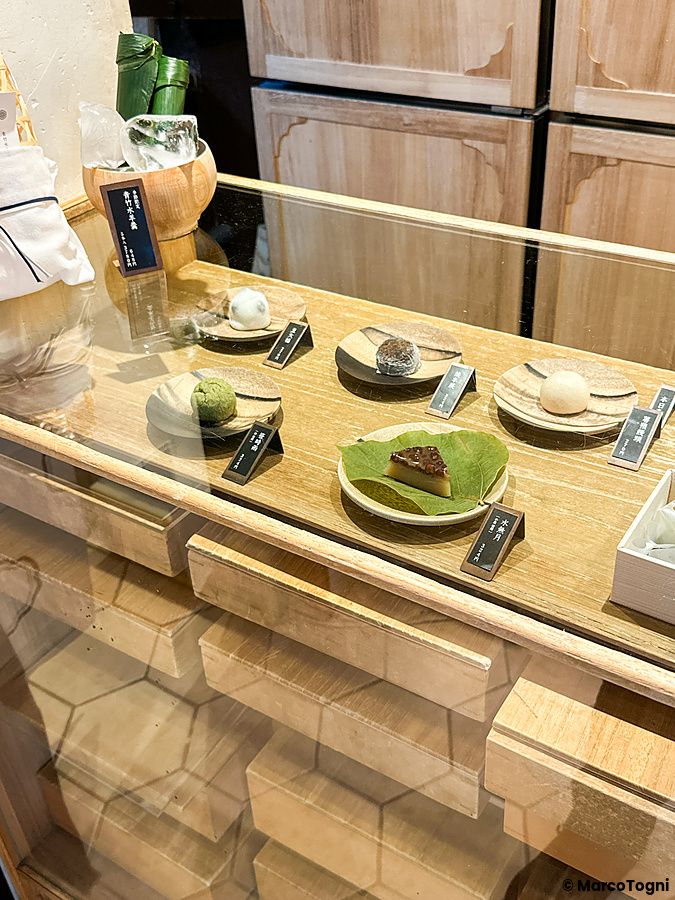 Vetrina in vetro con diversi dolci tradizionali giapponesi su piattini presso Sakurai Japanese Tea Experience a Tokyo.