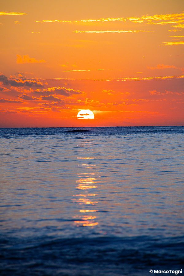 Tramonto sul mare a Mimikiri Beach, Okinawa, con cielo arancione e riflessi sull'acqua