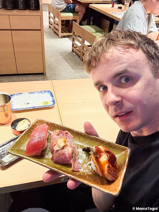Marco Togni tiene un piatto di sushi assortito in un ristorante.