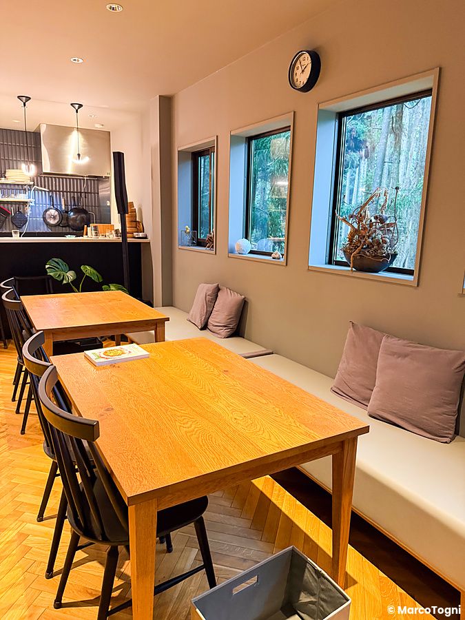 Veduta degli interni del ristorante VeganLife SoiSoi a Kyoto con tavoli in legno, panche e vista sulla vegetazione esterna.