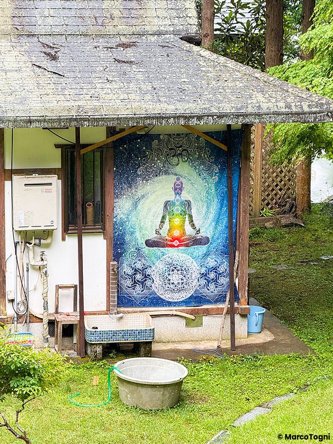Un arazzo con una figura in meditazione e i chakra appeso alla parete esterna del ristorante VeganLife SoiSoi a Kyoto.