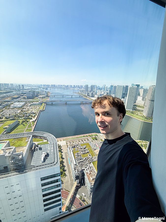 Marco Togni in primo piano scatta un selfie con vista dalla stanza a Mitsui Garden Hotel Toyosu Premier, Tokyo.
