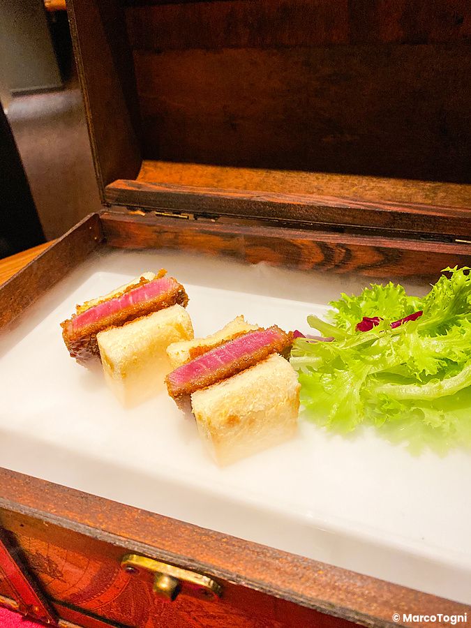 Due sandwich di wagyu katsu sando serviti in una scatola di legno al ristorante Cossott'e SP a Tokyo.