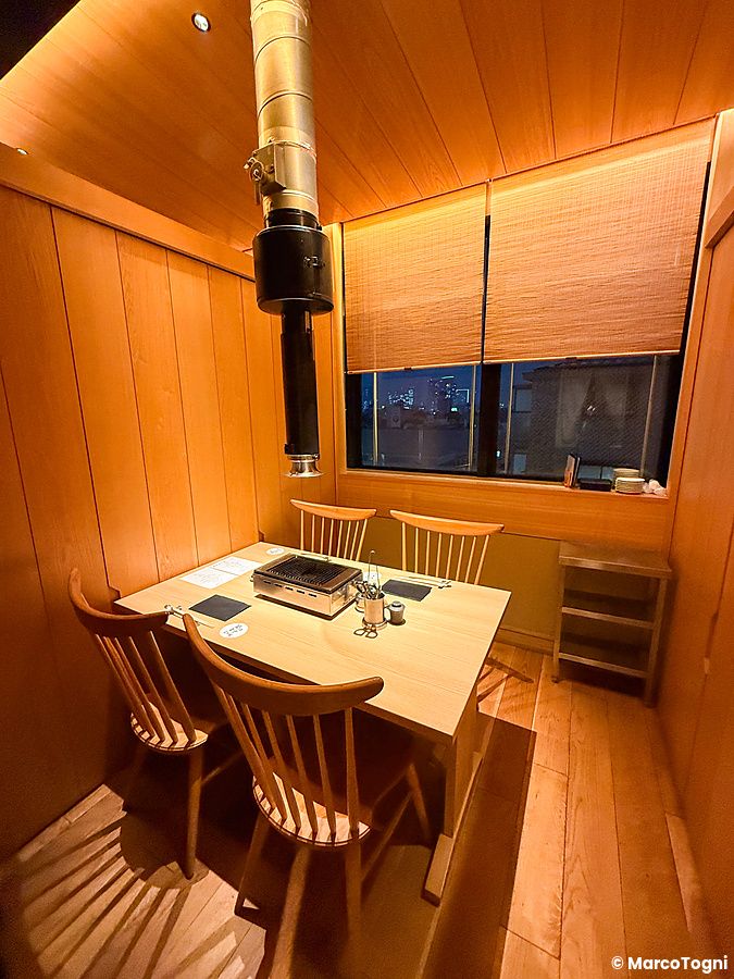 Tavolo con griglia a Yakiuo Ishikawa situato in una saletta in legno a Roppongi, Tokyo.