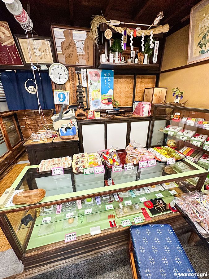 Interno della pasticceria Kikuzuki a Yanaka con vetrine di dolci tradizionali e arredi storici in legno.