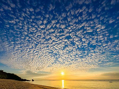 Tramonto dorato con nuvole a fiocchi sopra la spiaggia Mimikiri Beach a Okinawa.