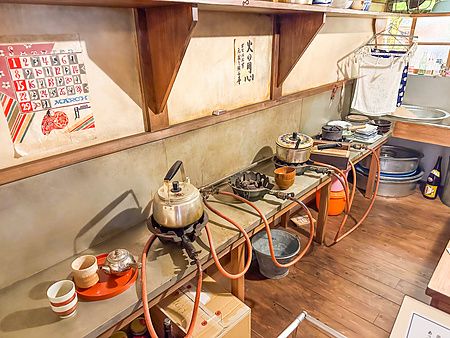 Veduta della cucina nella stanza del museo a Museo Manga Tokiwaso con fornelli, bollitori e un calendario alla parete.