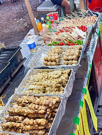 Banco di street food in Giappone con spiedini vari su teglie di alluminio.