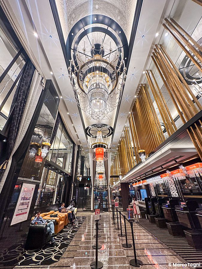 La spaziosa hall dell'Apa Hotel & Resort Roppongi-Eki-Higashi Station East con lampadari di cristallo e arredi moderni.
