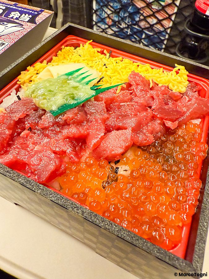 Un bento sullo shinkansen composto da tonno crudo, uova di salmone e strisce di uovo all'interno di una scatola.