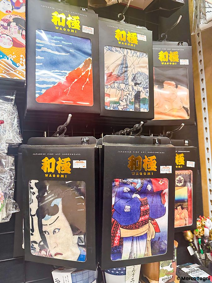 Boxer a tema Giappone esposti in confezioni nere su una griglia metallica nel negozio Village Vanguard.