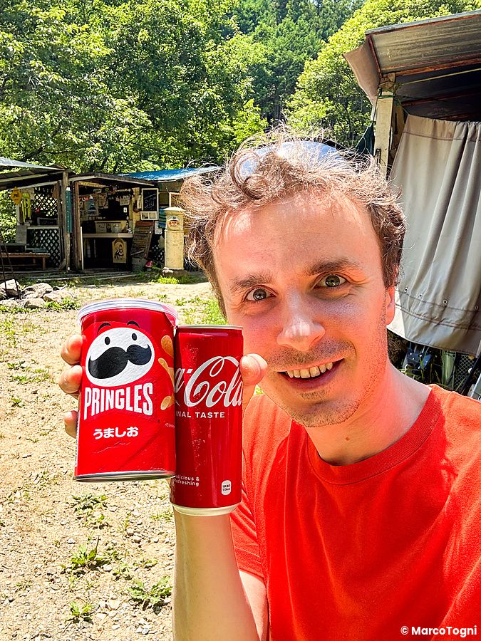Marco Togni in campeggio in Giappone con lattina di Pringles e Coca-Cola.