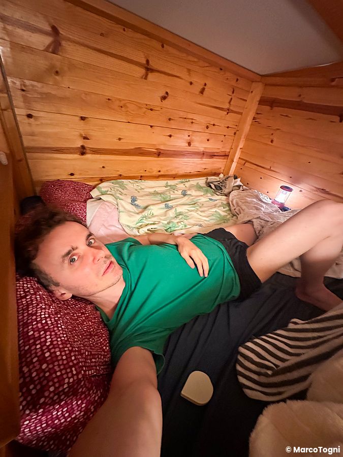 Marco Togni sdraiato in una piccola casetta di legno durante un campeggio.