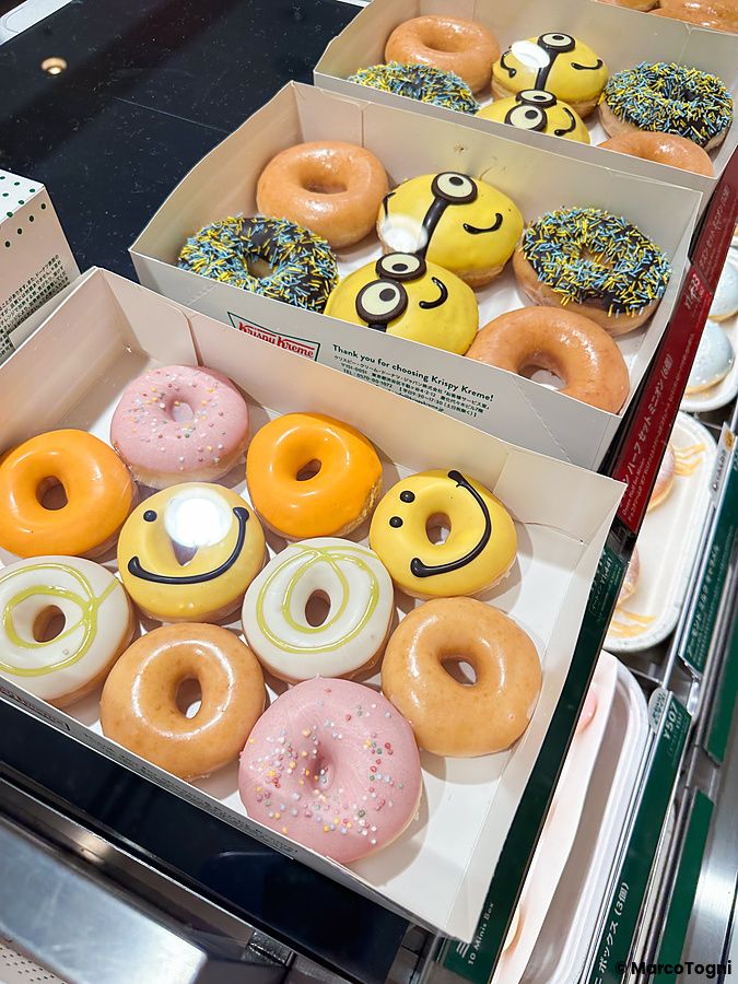 Due scatole di cartone riempite di ciambelle decorate e colorate esposte in una vetrina da Krispy Kreme in Giappone.