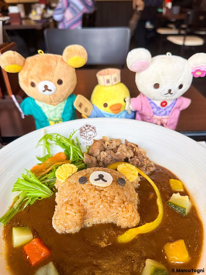 Un piatto di curry con riso a forma di orso alla Rilakkuma Tea House ad Arashiyama, con tre pupazzi sullo sfondo.