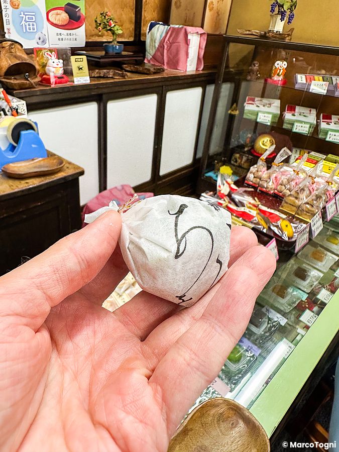 Una mano tiene il dolce Aoume confezionato all'interno della pasticceria Kikuzuki nel quartiere di Yanaka a Tokyo.