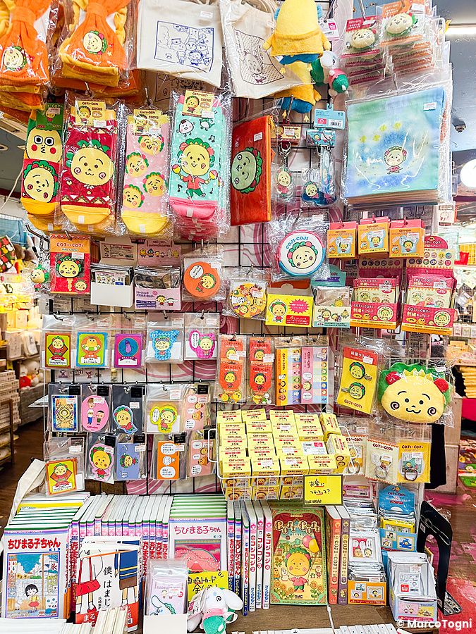 Gadget del manga Coji-Coji esposti su una griglia metallica in un negozio Village Vanguard in Giappone.